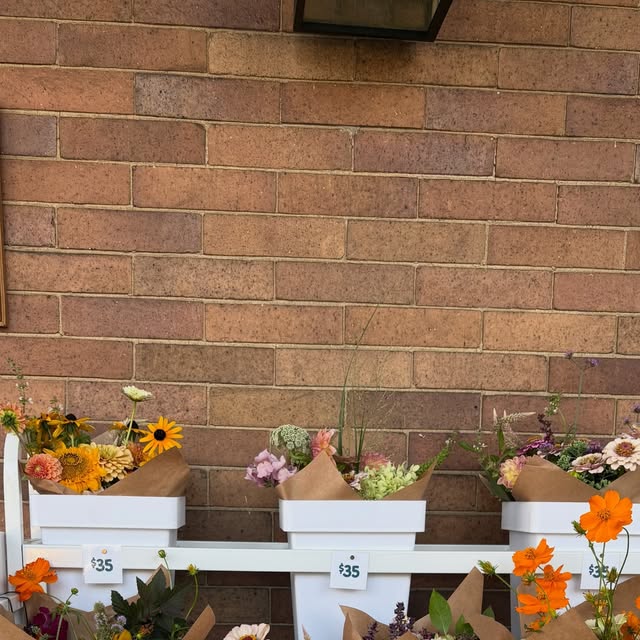Bouquets arranged in white buckets across the brick porch stand